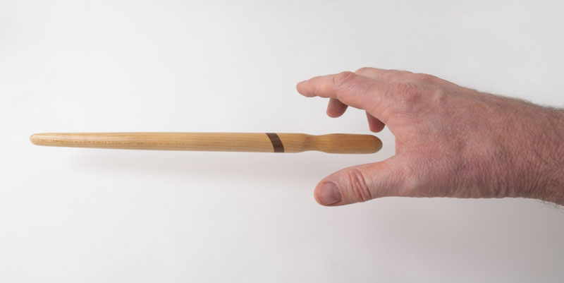 Hand reaching for a spirtle, or spurtle, in birch and walnut