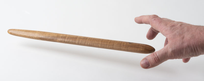 Hand reaching for a spirtle, or spurtle, in oak